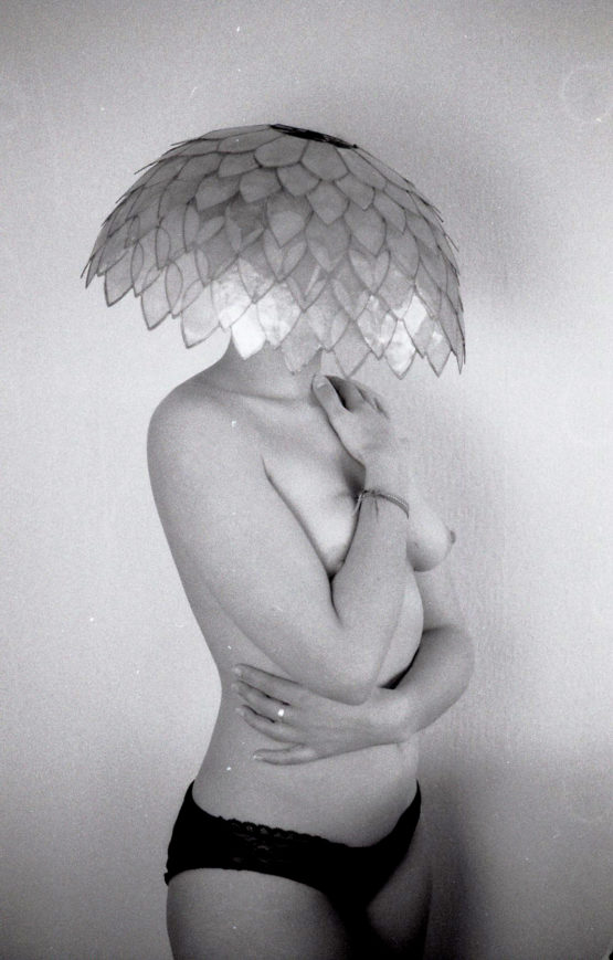 Photographie d'une femme nue portant sur la tête un abat jour en écailles